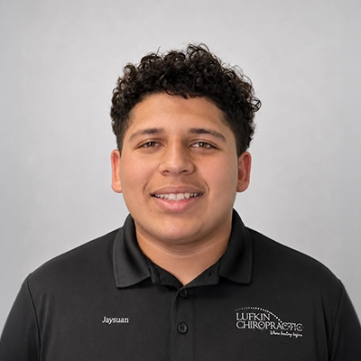 Chiropractic Assistant Jaysuan Feliciano Smiling In Front Of Grey Background