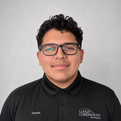 Chiropractic Assistant Josuan Feliciano Smiling In Front Of Grey Background
