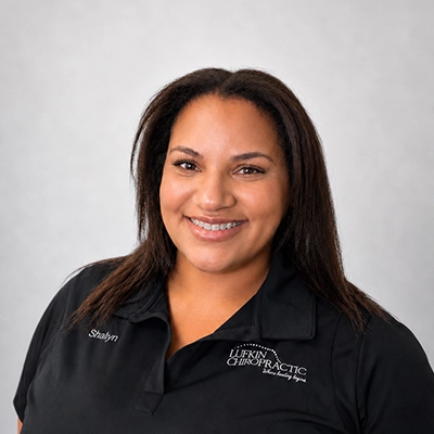 Marketing Manager Shalyn Cofer Smiling In Front Of Grey Background