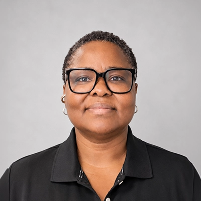 Licensed Massage Therapist Sophia Emenanjo Smiling In Front Of Grey Background