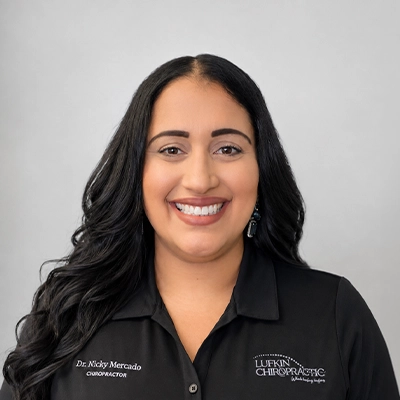 Chiropractor Nicole Mercado Smiling In Front Of Grey Background